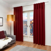 Roter Dekoschal J!Fina 130x250 cm, frontal vor einem Fenster in einem gemütlichen Wohnzimmer mit grauem Sofa und Stehlampe.