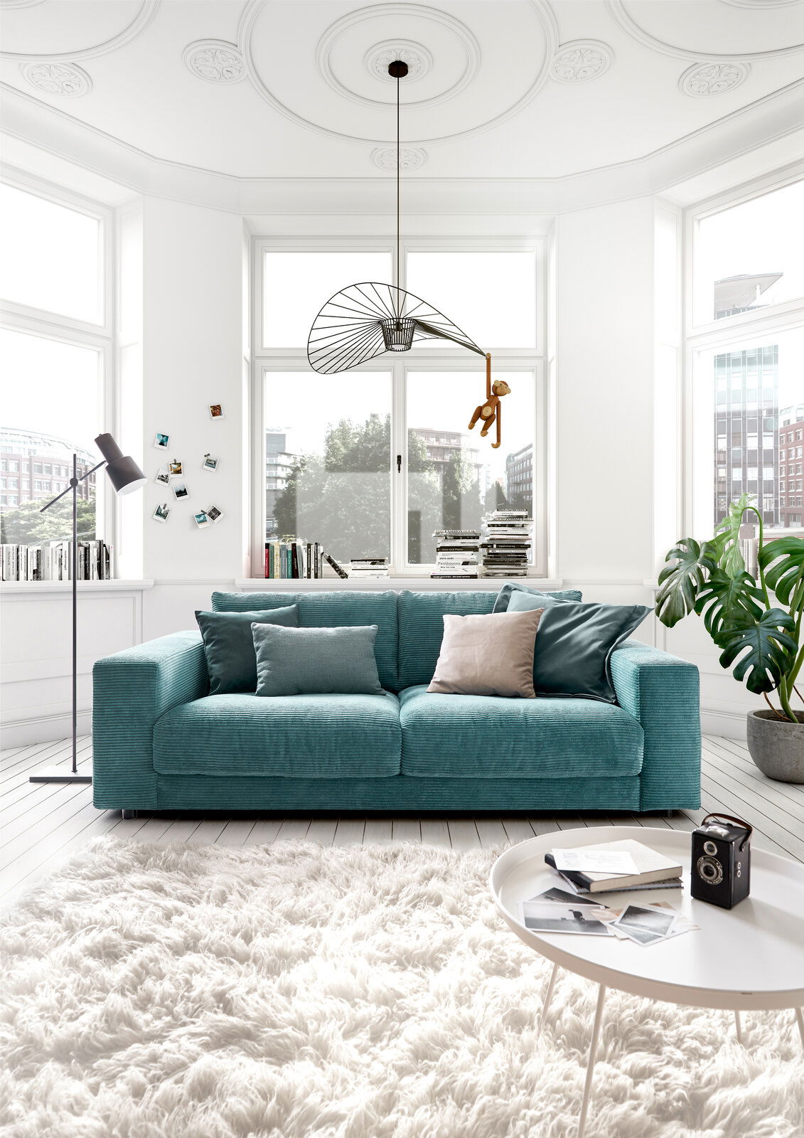 Zweiersofa in Türkis in einem hellen Wohnzimmer mit großen Fenstern, von vorne gesehen.