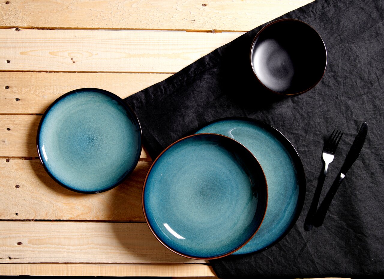 Ritzenhoff & Breker Tafelset 18-tlg. BALI Vogelperspektive auf ein 18-teiliges Teller-Set Bali mit türkisfarbenen Tellern und einer schwarzen Schale auf einem Holztisch mit schwarzer Tischdecke.