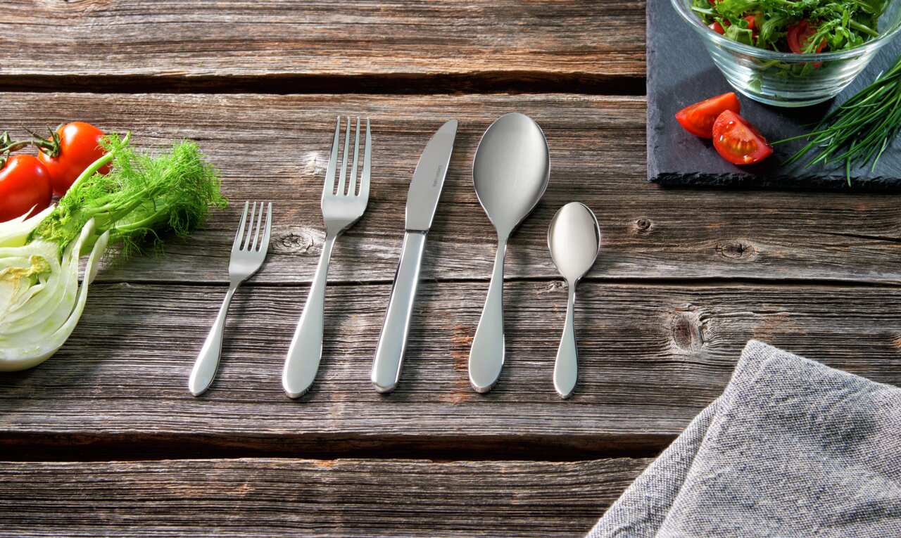 Besteckset 30-tlg. auf rustikalem Holztisch, bestehend aus Gabel, Messer, Esslöffel, Teelöffel und Salatgabel, von oben fotografiert.