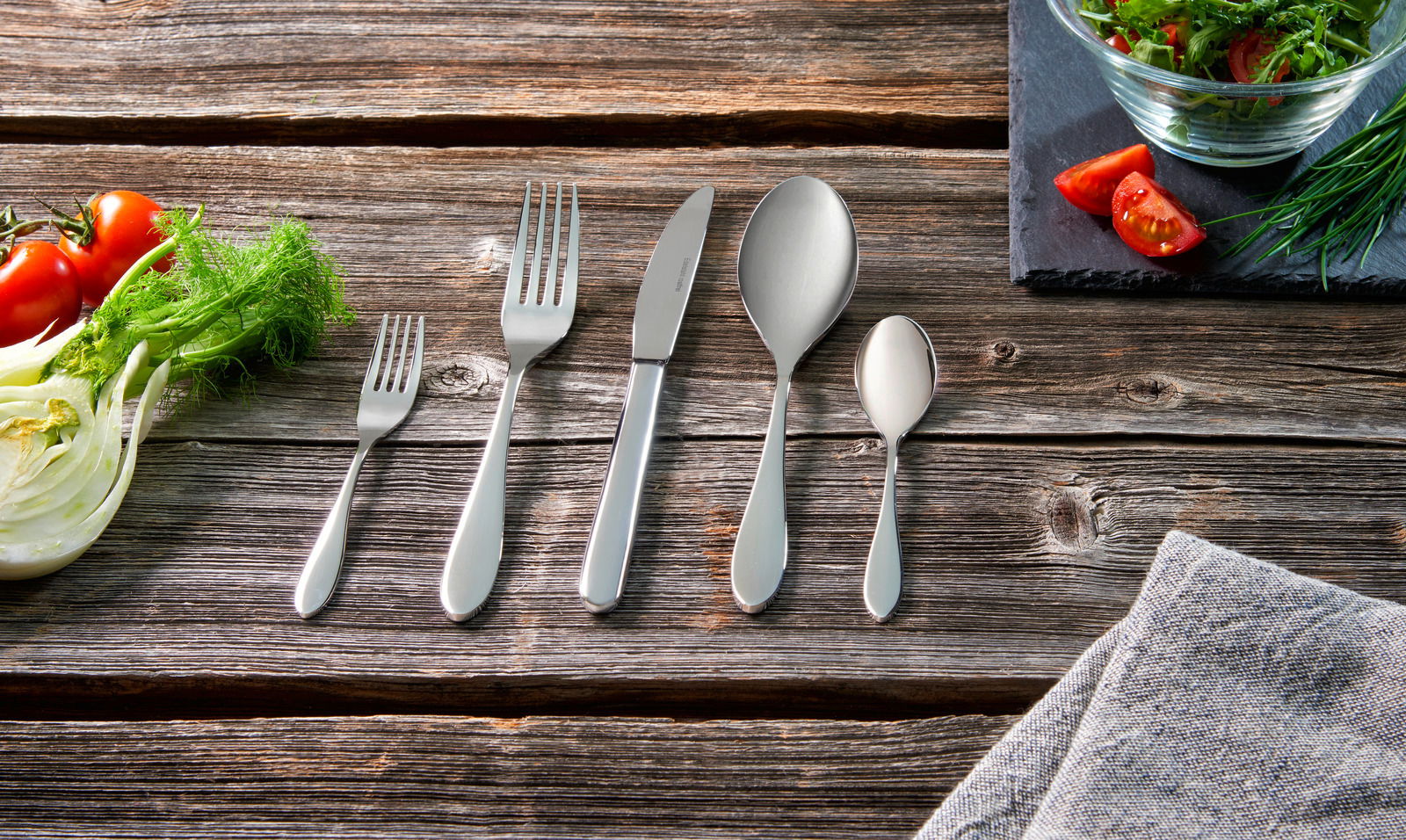 Besteckset 30-tlg. auf rustikalem Holztisch, bestehend aus Gabel, Messer, Esslöffel, Teelöffel und Salatgabel, von oben fotografiert.