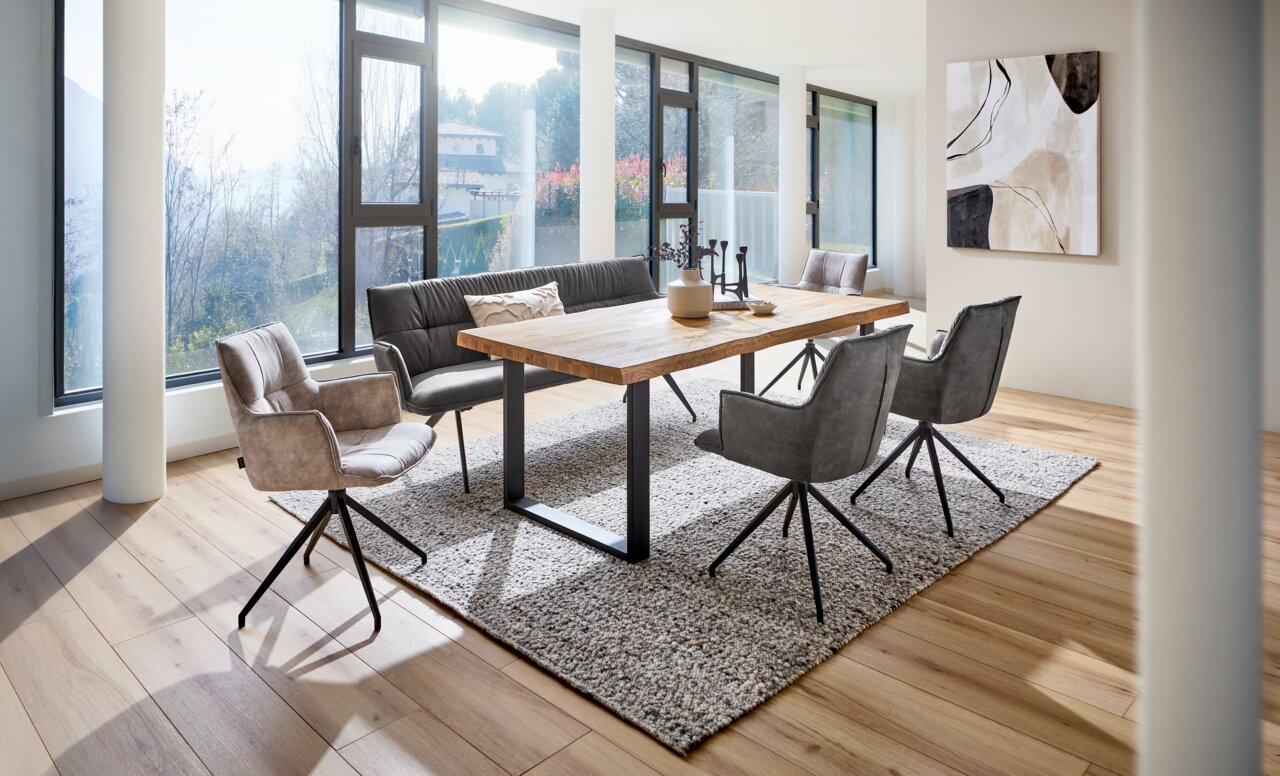 Moderner Esstisch 160x90 aus Holz mit Metallbeinen, umgeben von stilvollen Stühlen in einem hellen, lichtdurchfluteten Raum mit großen Fenstern, seitliche Perspektive.