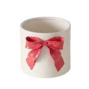 Weißer Übertopf aus Porzellan mit roter Schleife, frontal fotografiert.