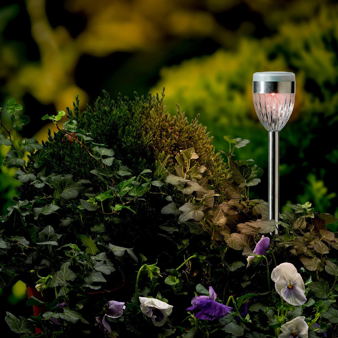 Solar Stabbeleuchtung in einem Garten, seitliche Perspektive, umgeben von grünen Pflanzen und Blumen.