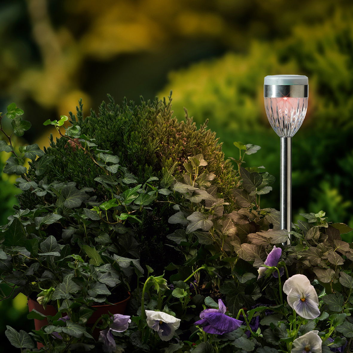 Solar Stabbeleuchtung in einem Garten, seitliche Perspektive, umgeben von grünen Pflanzen und Blumen.