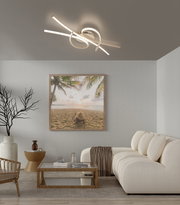 Moderne LED-Deckenleuchte in geschwungenem Ring- und Stabdesign in warmweißem Licht, an der Decke montiert, Ansicht von unten in einem Wohnzimmer.