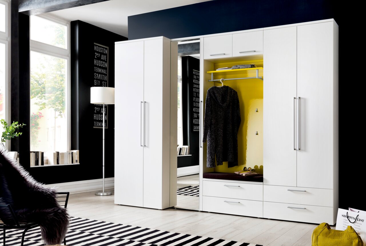 Moderne weiße Garderobe mit gelbem Innenraum, Kleiderhaken und Schubladen, seitliche Perspektive