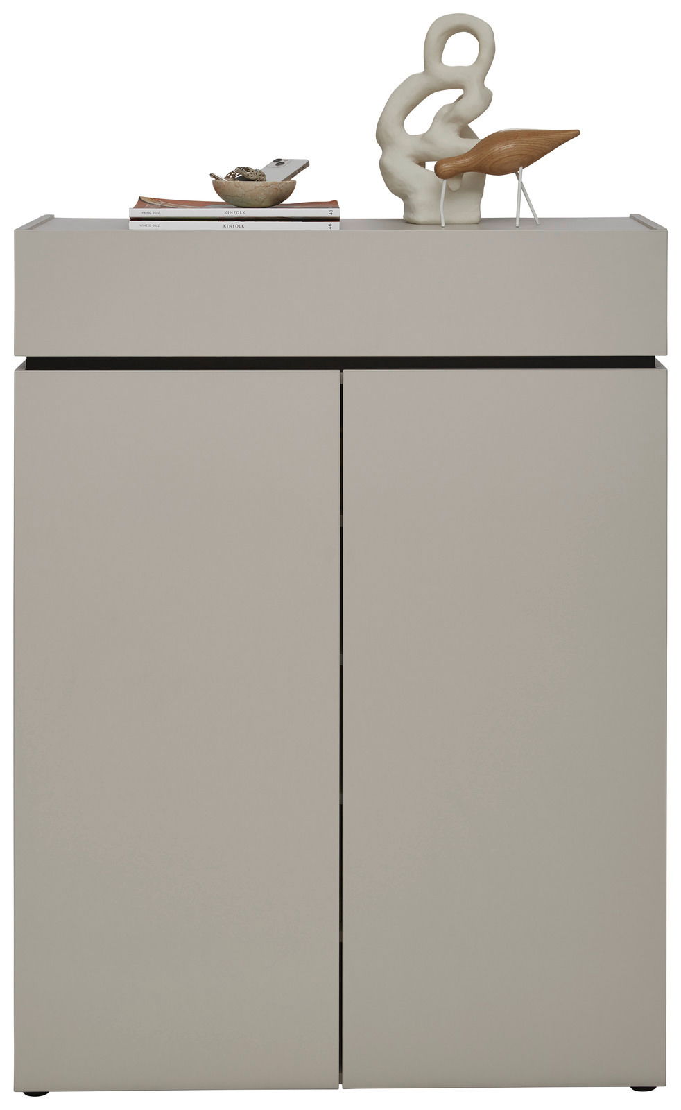 Moderner Schuhschrank in grauer Farbe mit zwei Türen, dekoriert mit einer Skulptur und Büchern auf der Oberseite, Frontalansicht.