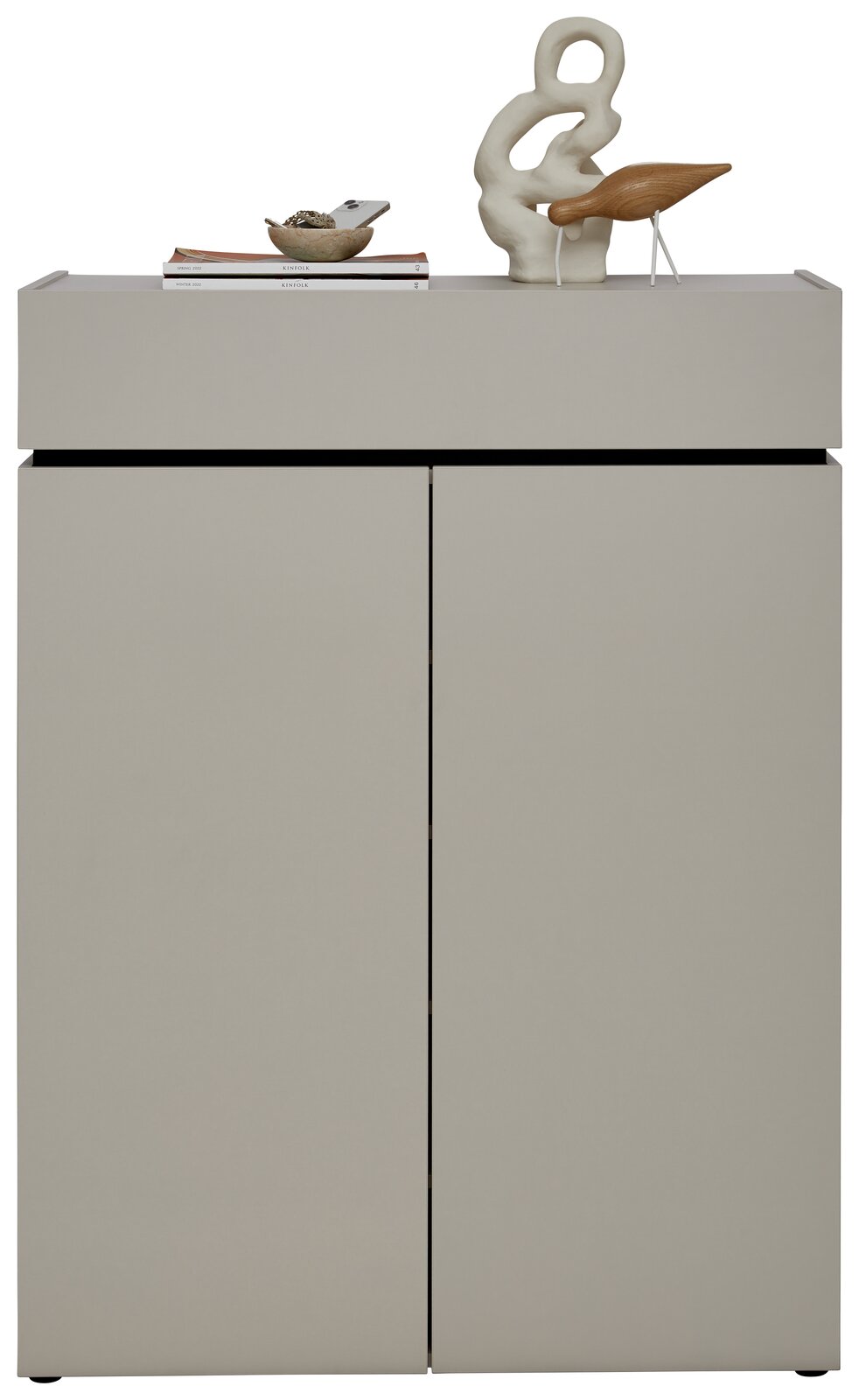 Moderner Schuhschrank in grauer Farbe mit zwei Türen, dekoriert mit einer Skulptur und Büchern auf der Oberseite, Frontalansicht.