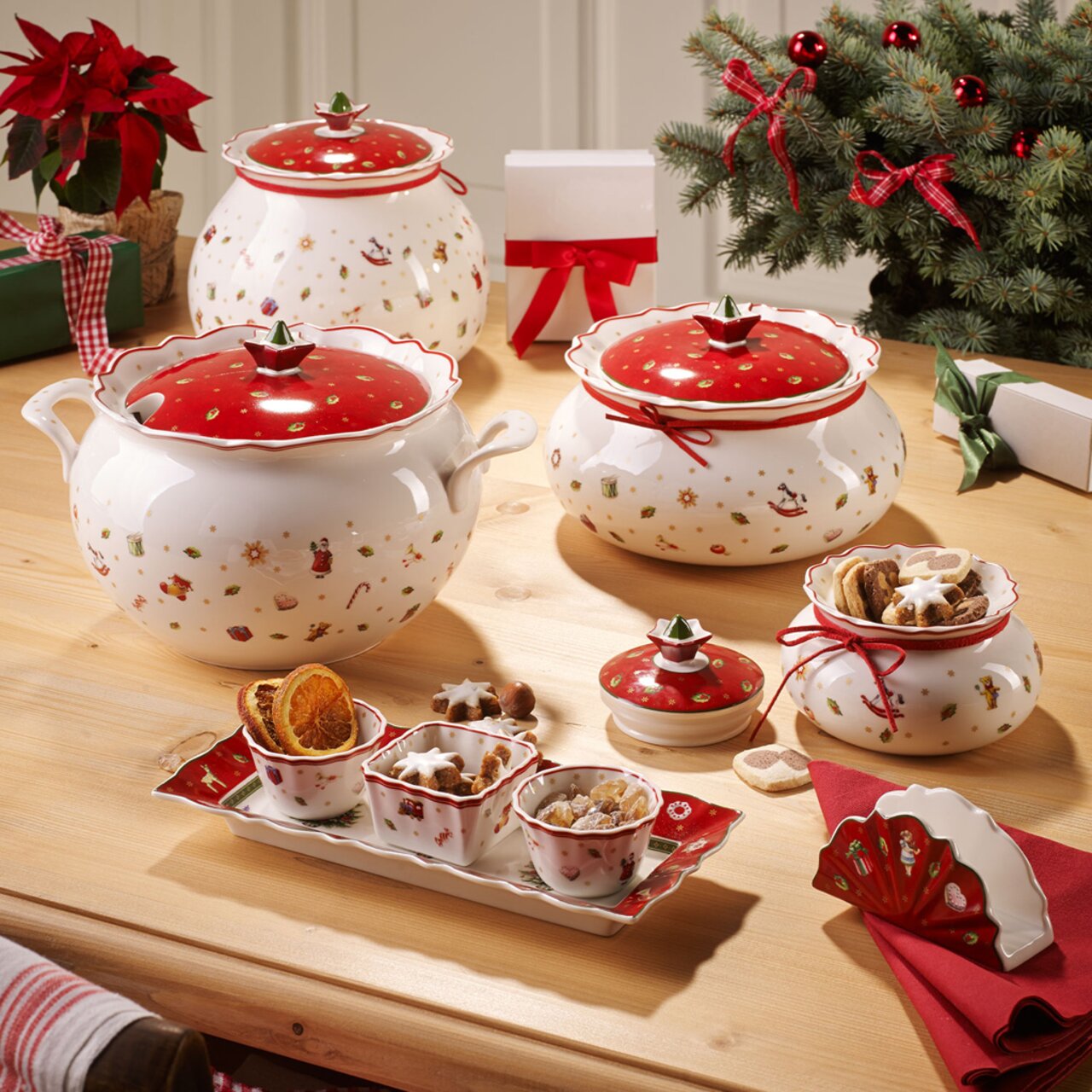 Weihnachtliches Dip-Set mit vier Teilen, bestehend aus dekorativen Schalen und Deckeln in Rot und Weiß mit festlichen Motiven, auf einem Holztisch arrangiert. Perspektive von oben.
