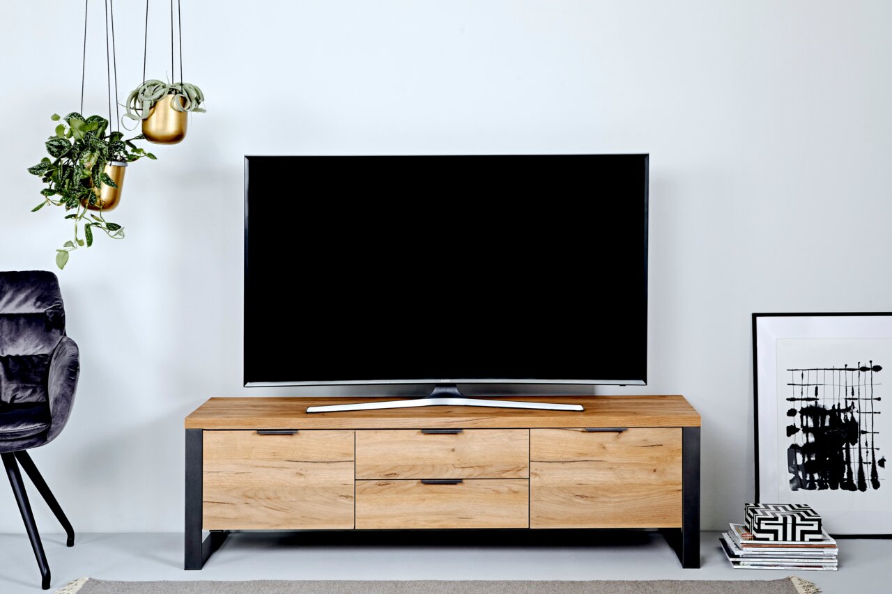 Houten tv-kast met metalen accenten, gezien vanaf de voorkant, versierd met een tv, planten en kunstwerken.