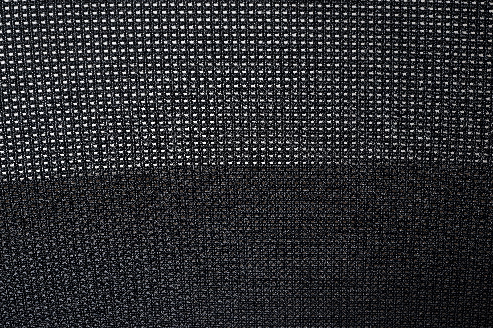 Nahaufnahme des Netzgewebes eines Drehstuhls, von vorne betrachtet.