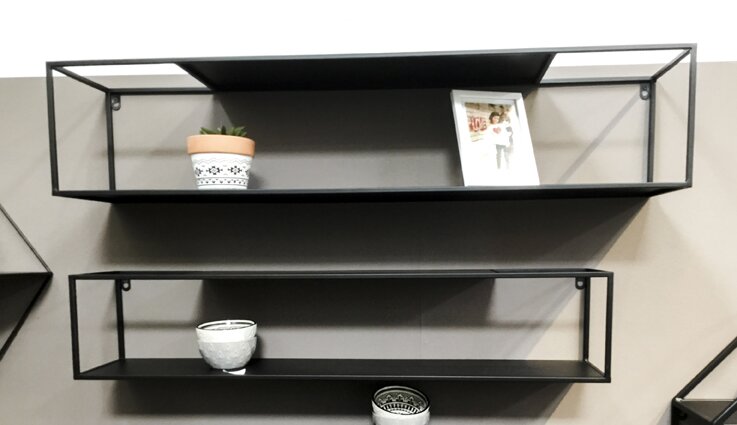 Zwei schwarze, rechteckige Wandregale aus Metall im Industrial-Design an einer grauen Wand, frontal aus leicht schräger Perspektive von links fotografiert mit kleinem Blumentopf, Schale und Bilderrahmen dekoriert.