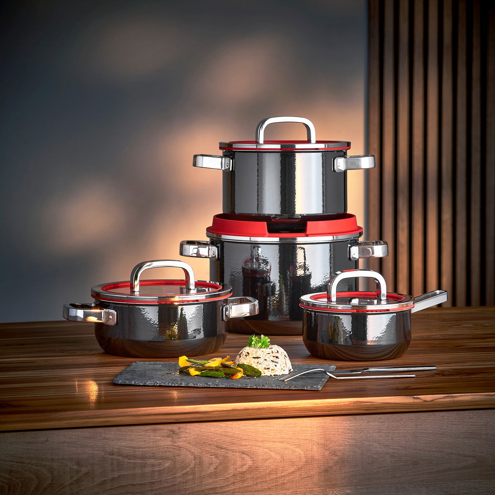 WMF Topfset 4-tlg. FUSIONTEC Topfset Fusiontec Black 4-tlg. in eleganter schwarzer Ausführung mit roten Akzenten, auf einem Holztisch präsentiert, seitliche Perspektive.