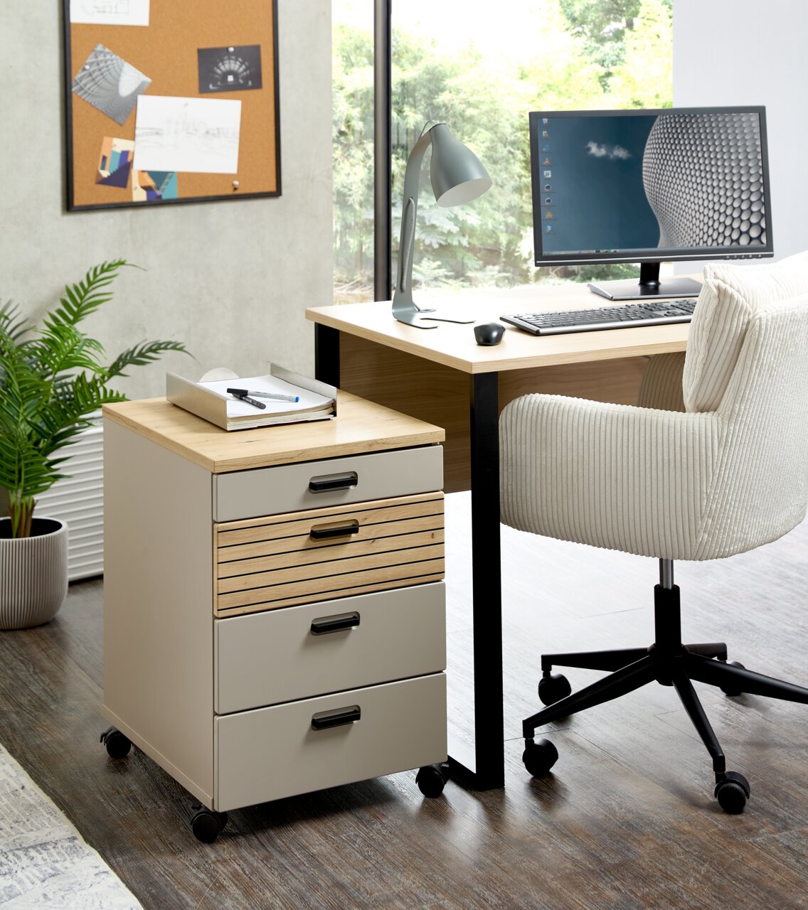 Rollcontainer mit vier Schubladen, auf Rollen, in einem modernen Büro neben einem Schreibtisch und einem Stuhl, aus der Perspektive von vorne links.