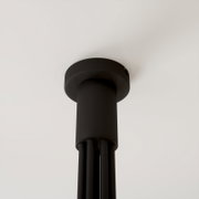 Zwarte, cilindervormige plafondlamp met ronde plafondrozet, close-up vanuit de onderkant (van onder naar boven gezien)