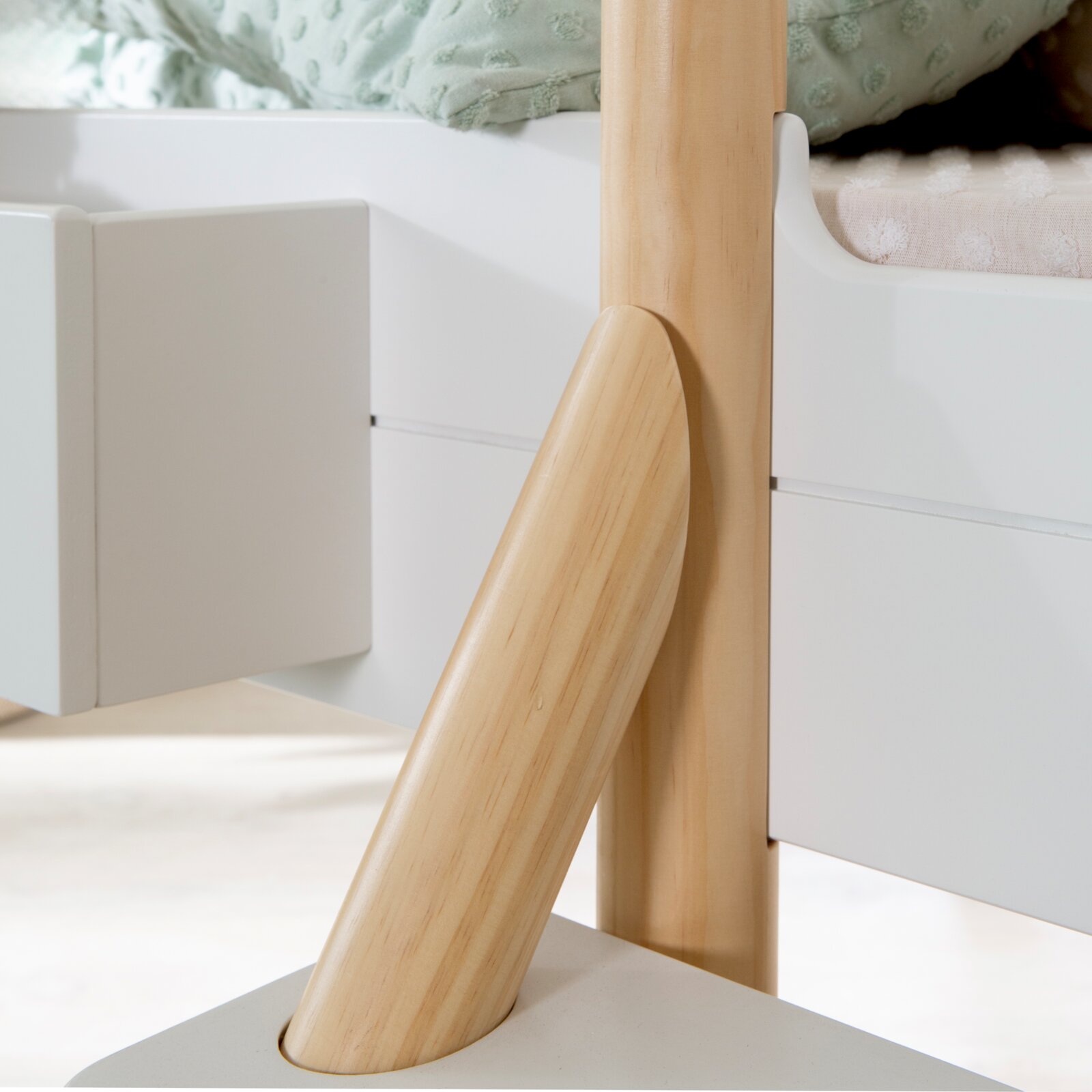Detailansicht aus seitlicher Nahperspektive auf ein weißes Kinderhochbett mit naturfarbenem Holzpfosten und schrägem Leiterholm.