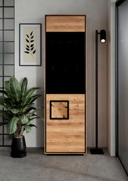Frontansicht eines modernen Holz-Pelletofens in Eiche-Optik mit schwarzer Glasfront und Sichtfenster, freistehend in einem Wohnraum neben Stehlampe und Zimmerpflanze.