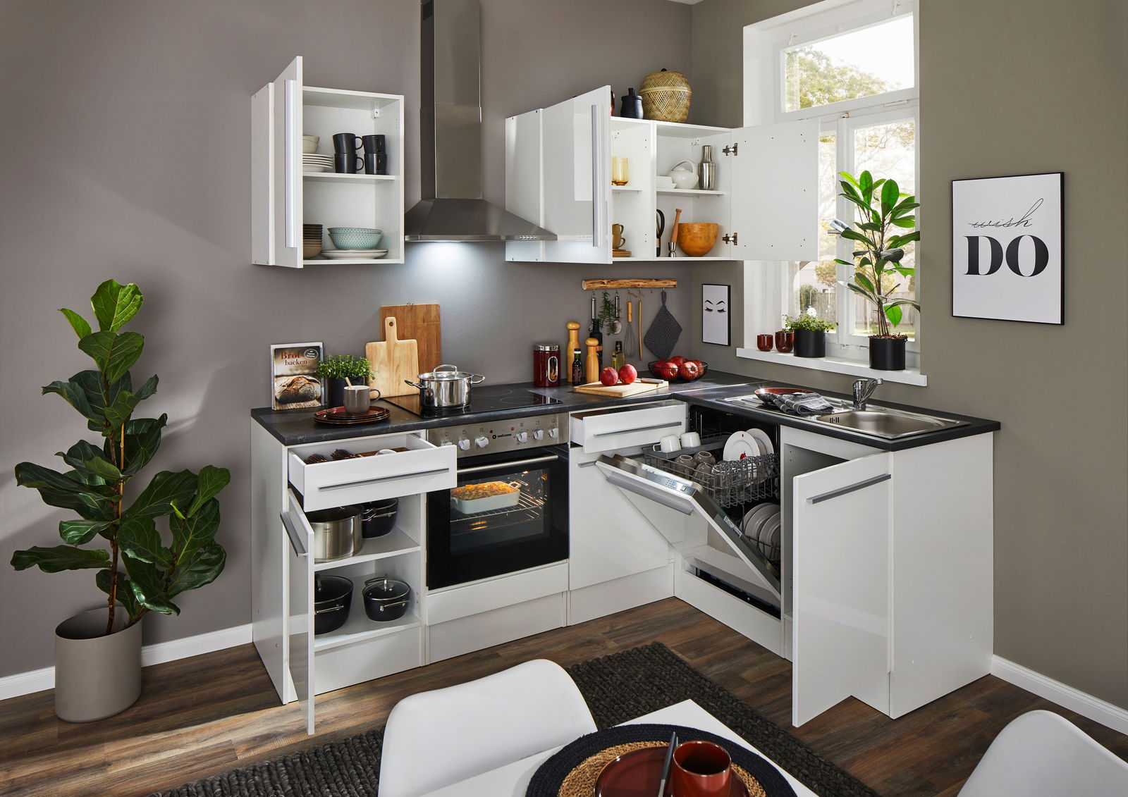 Moderne weiße Eckküche mit geöffneten Schränken und Schubladen, Blick von vorne. Integrierte Geräte wie Herd und Geschirrspüler, dekoriert mit Pflanzen und Küchenutensilien.