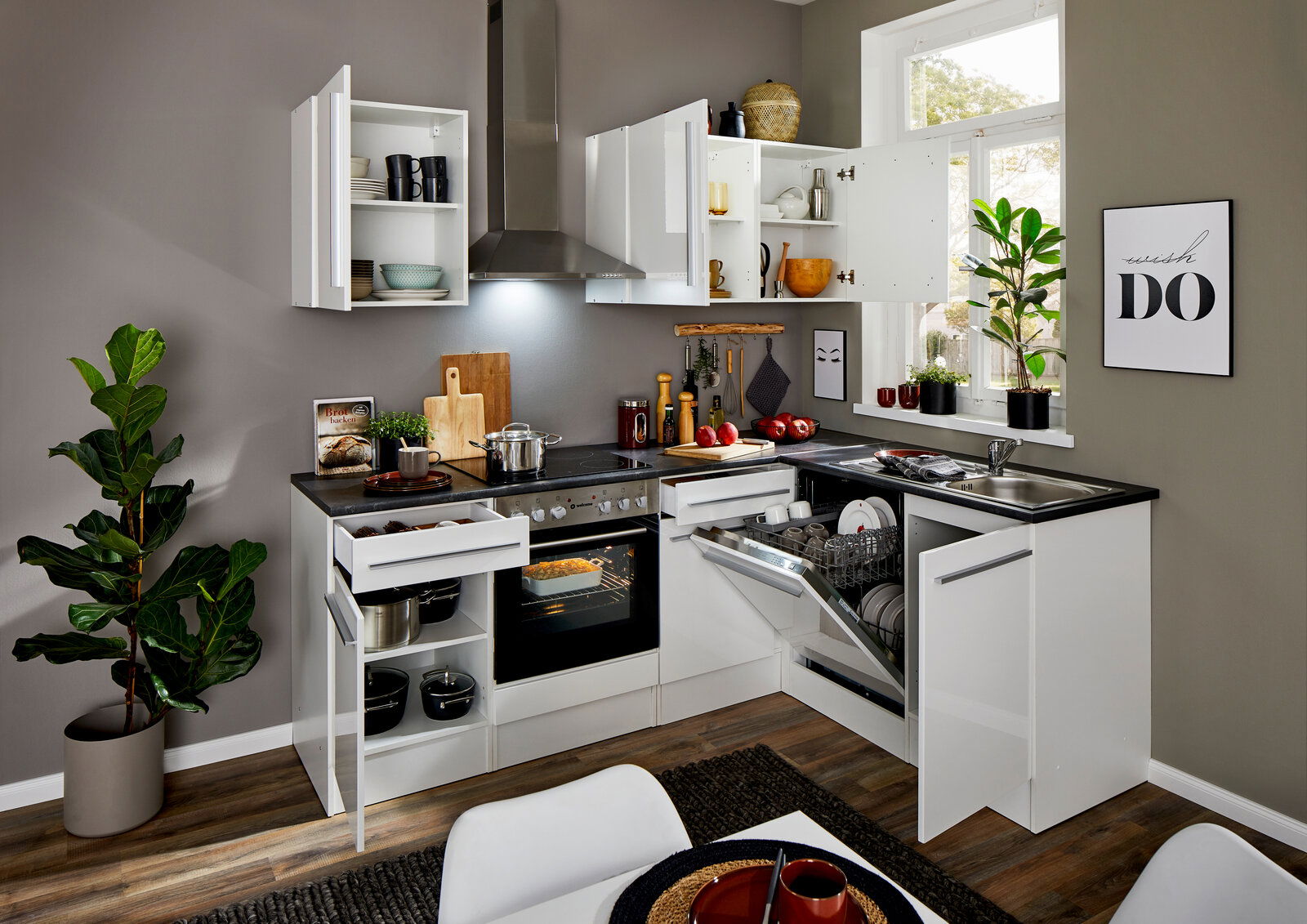 Moderne weiße Eckküche mit geöffneten Schränken und Schubladen, Blick von vorne. Integrierte Geräte wie Herd und Geschirrspüler, dekoriert mit Pflanzen und Küchenutensilien.