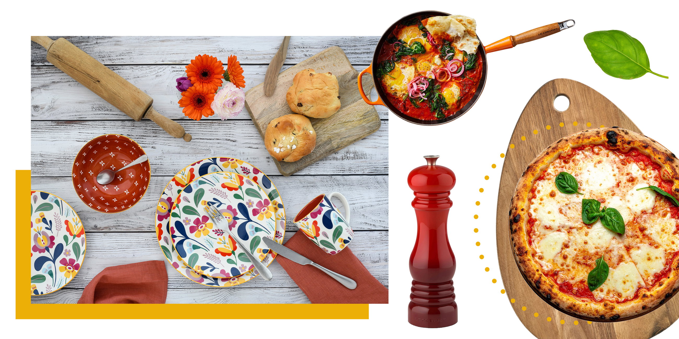 Bunter Frühstückstisch mit floralem Geschirr, Brötchen, Pfanne mit Shakshuka und Pizza auf Holzbrett