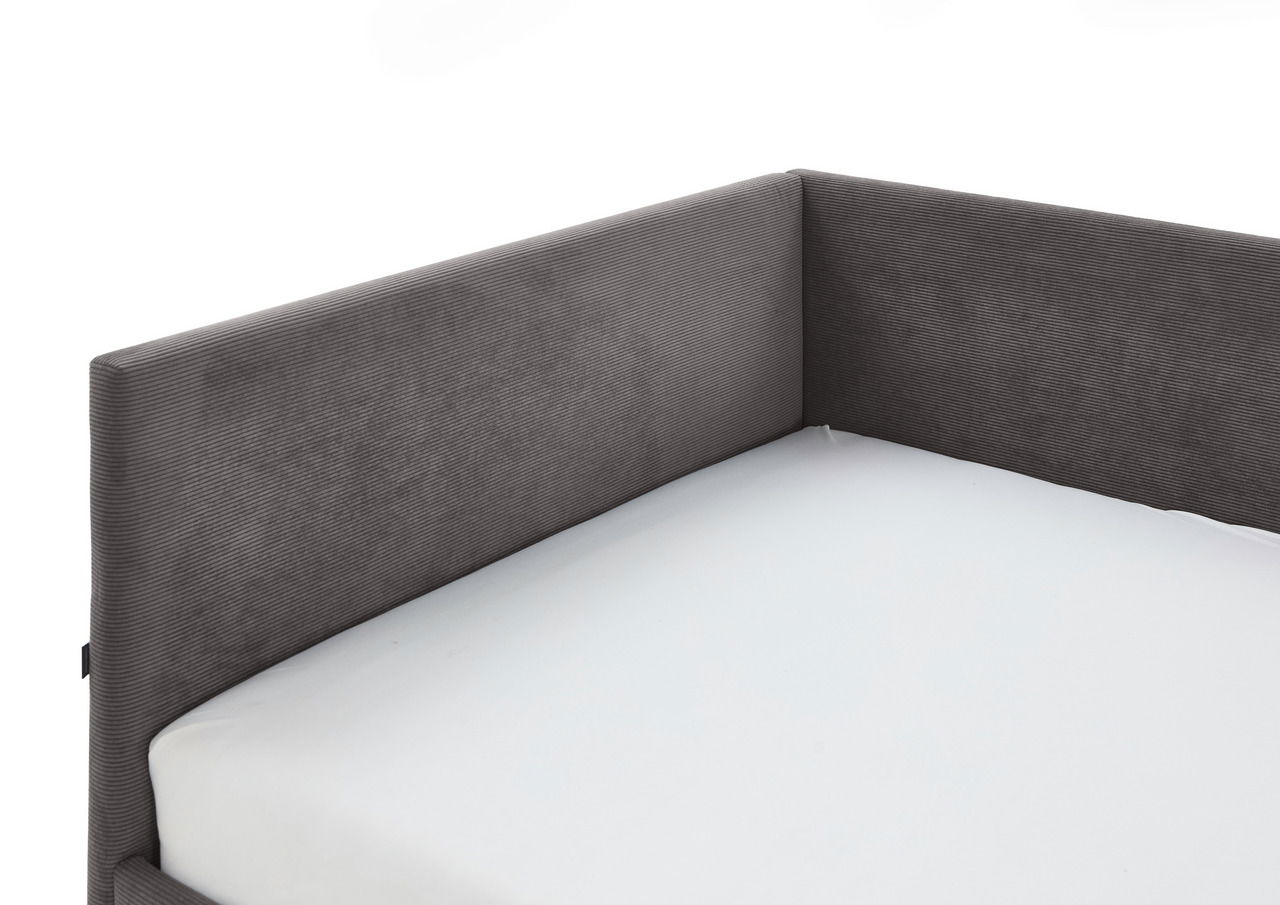 Eckansicht einer grauen Polsterliege mit weißer Matratze, die eine moderne und elegante Ausstrahlung vermittelt.