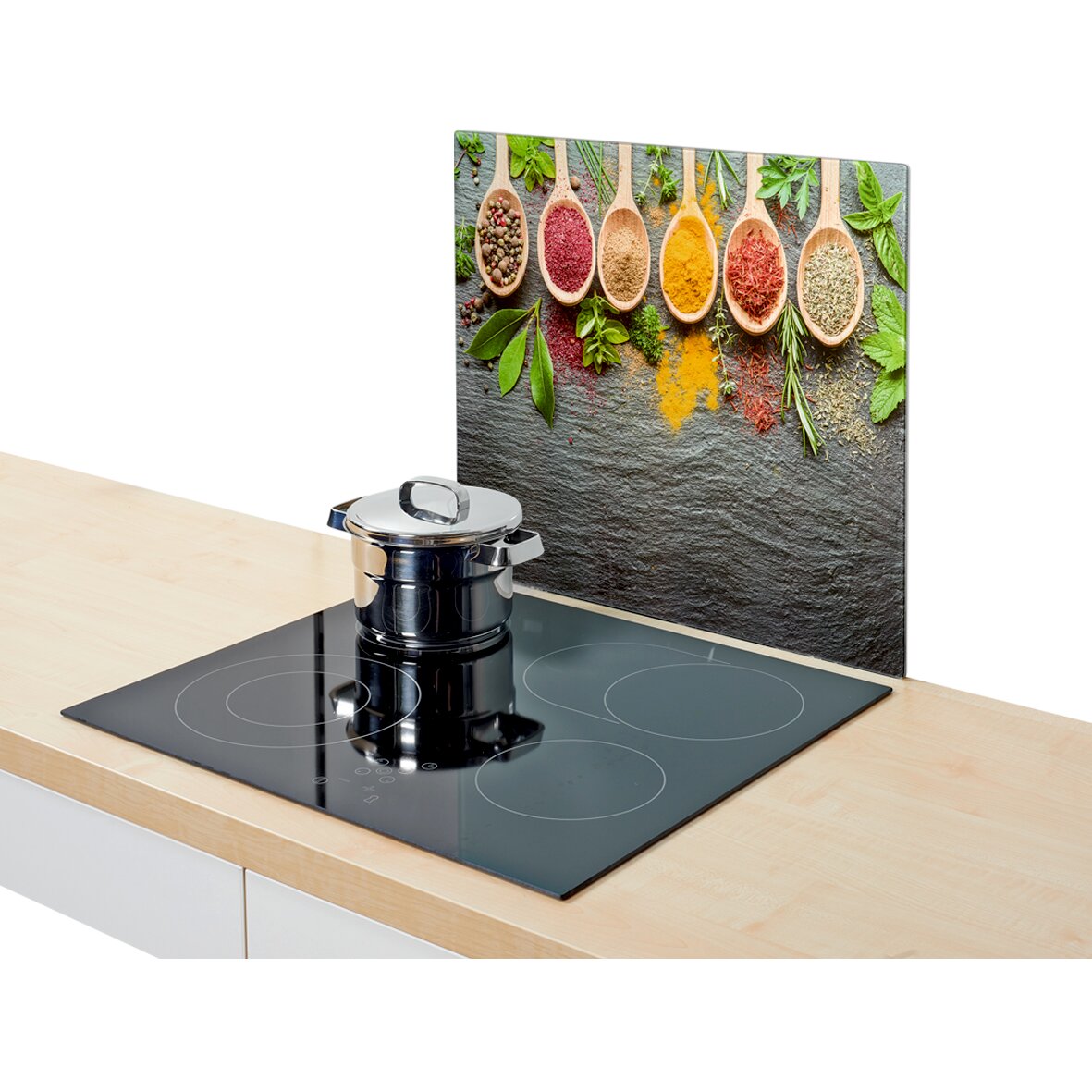 Herdblende mit buntem Gewürzmotiv, fotografiert aus seitlicher Perspektive neben einem modernen Kochfeld mit Topf.