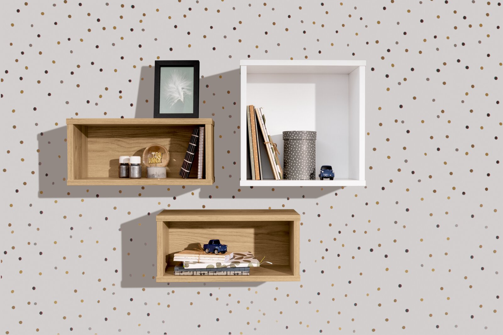 Drei Wandboxen in rechteckiger Form, zwei in Holzoptik und eine in Weiß, an einer gepunkteten Wand montiert. Perspektive von vorne.