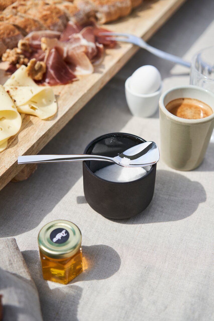 Eleganter Löffel aus dem Besteckset King 68-tlg., auf einem Tisch mit Frühstückszutaten, aus der Vogelperspektive fotografiert.