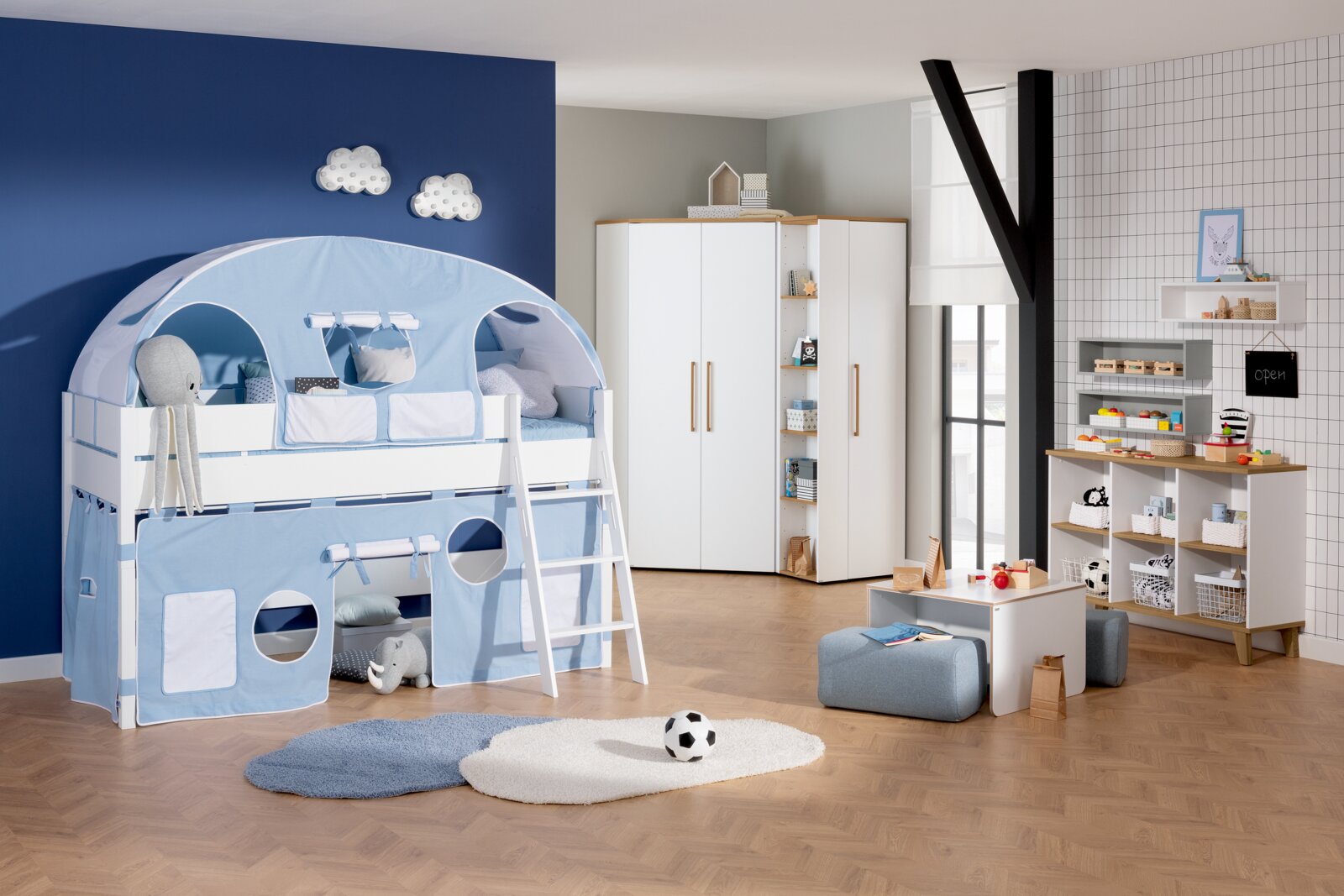 Spielbett Paidi TIAGO in einem Kinderzimmer mit blauer Zeltabdeckung und Leiter, aus der Perspektive von vorne links.