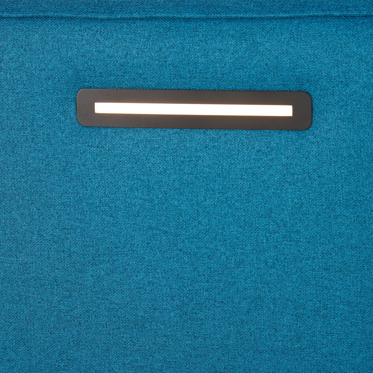 Nahaufnahme eines blauen Boxspringbetts mit integrierter Beleuchtung im Kopfteil.