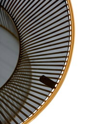 Nahaufnahme eines runden Beistelltisches mit einem goldenen Rahmen und einem Gitterdesign, von oben betrachtet.