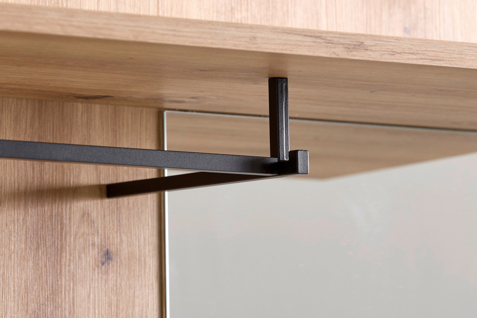 Nahaufnahme einer Kompaktgarderobe mit Holzoberfläche und schwarzer Metallstange, seitliche Perspektive.