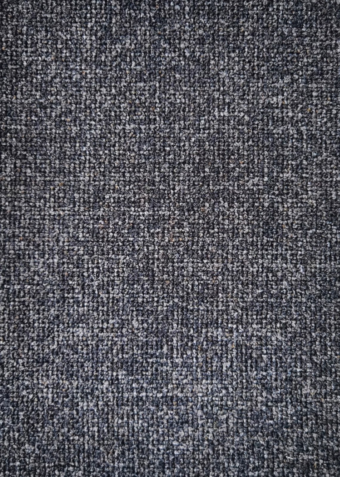 Nahaufnahme eines grauen, strukturierten Stoffes, von oben betrachtet