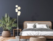 Moderne Stehleuchte mit mehreren runden Lampenschirmen in einem stilvoll eingerichteten Schlafzimmer, seitliche Perspektive.