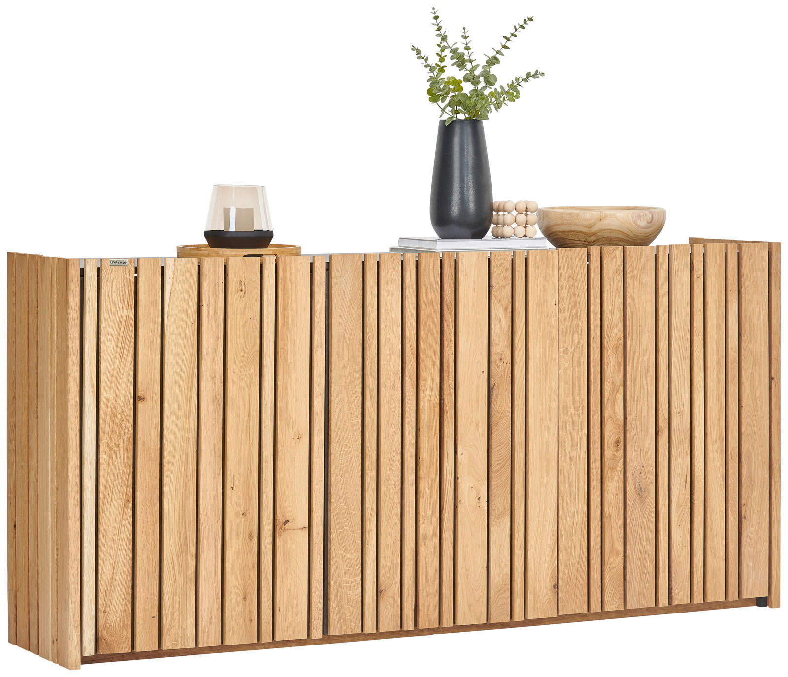 Frontale Ansicht eines modernen Sideboards aus hellem Holz mit vertikalen Lamellen, dekoriert mit einer Vase, einem Buch, einer Schale und einem Kerzenhalter.