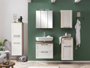 Moderner Badezimmer-Unterschrank in Weiß mit Holzdetails, frontal vor einer grünen Wand montiert.