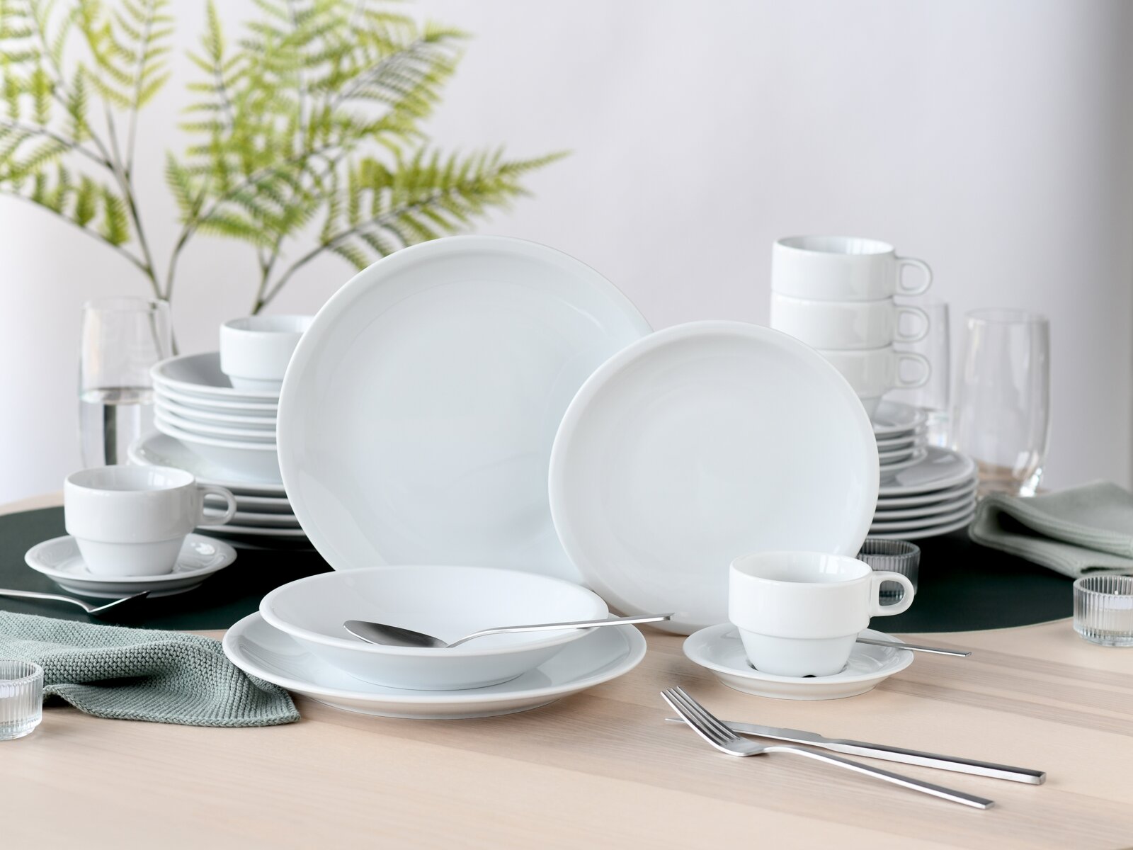 creaTable Kombiservice 30-tlg MILANO Weißes Porzellan-Geschirrset mit Tellern, Schalen und Tassen auf gedecktem Tisch, Perspektive: leicht schräg von vorn in Augenhöhe
