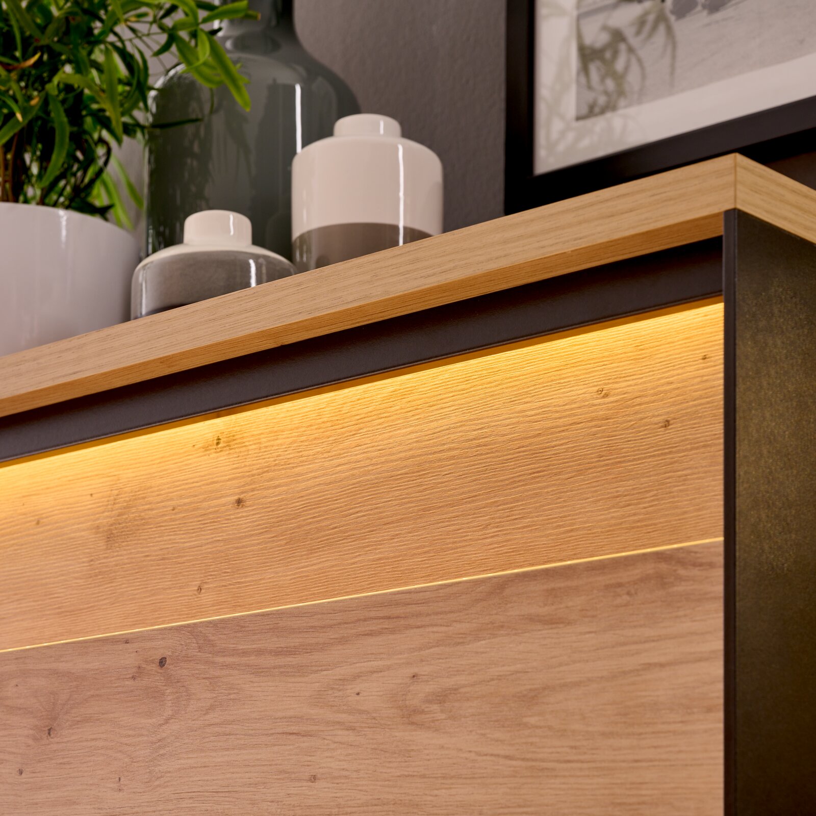 Detailfoto van een vitrinekast met houten afwerking en ingebouwde verlichting, gefotografeerd van bovenaf.