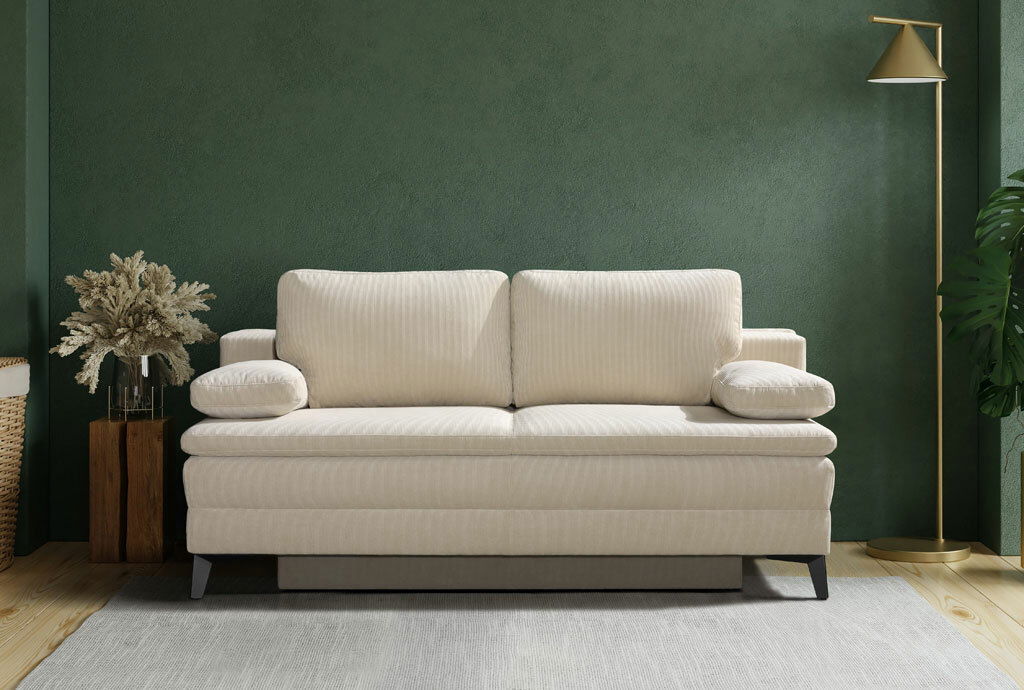 Novel Schlafsofa CHARLIZE Beige Querschläfer-Sofa in einem modernen Wohnzimmer, frontal betrachtet, mit grüner Wand und stilvoller Dekoration.