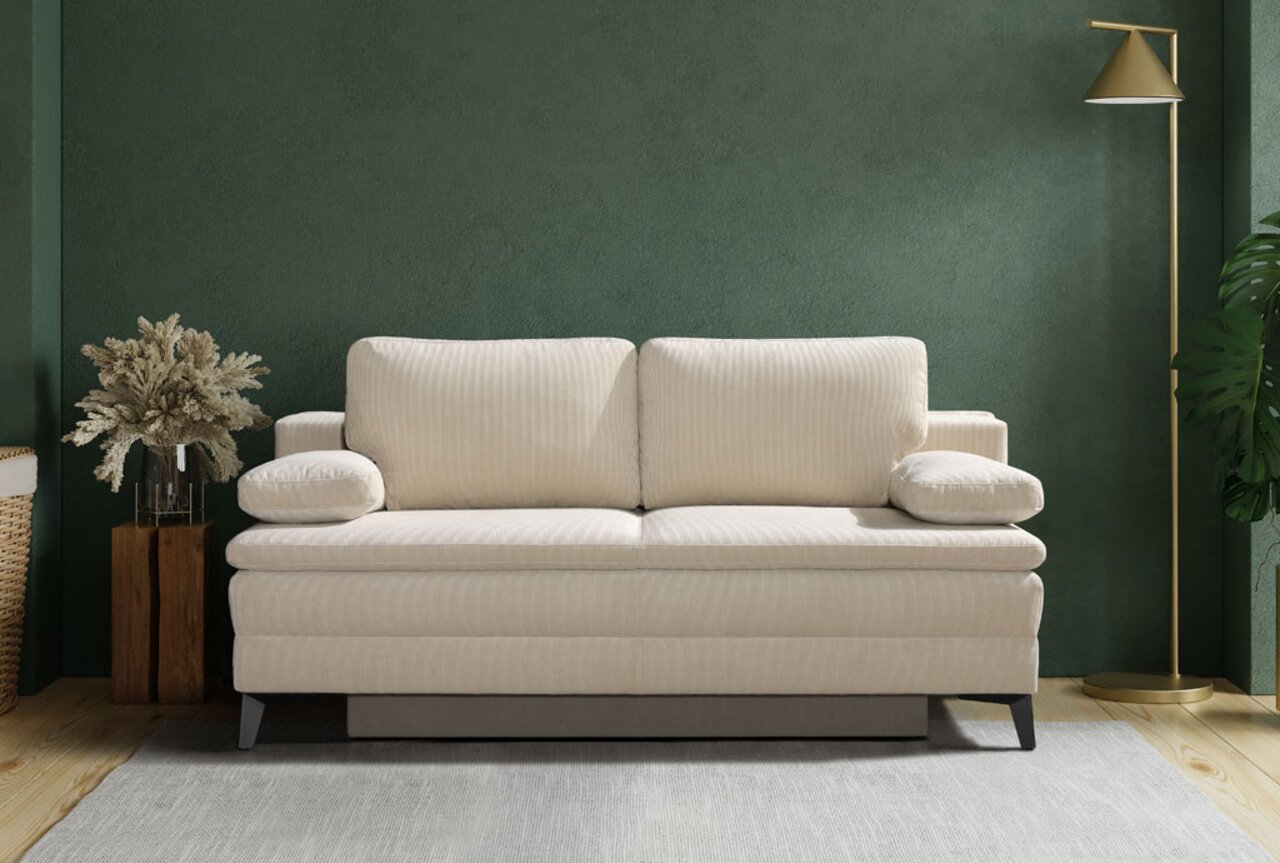 Beige Querschläfer-Sofa in einem modernen Wohnzimmer, frontal betrachtet, mit grüner Wand und stilvoller Dekoration.