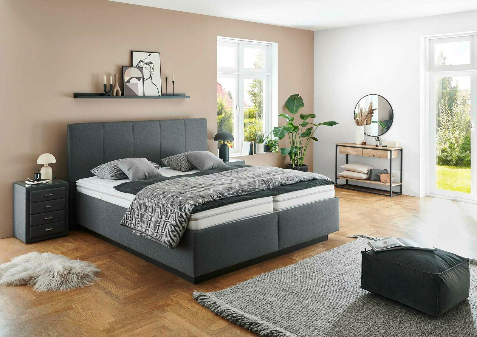 Modernes graues Polsterbett in einem stilvoll eingerichteten Schlafzimmer mit Blick auf das Bett von der Seite.