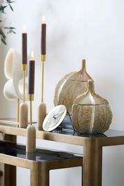 Dekorative Box in Form eines Kürbisses auf einem Tisch, umgeben von eleganten Kerzenhaltern und Büchern, seitliche Perspektive.