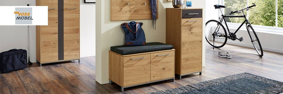 Ein moderner Flur mit Holzmöbeln, Sitzbank, Garderobe und einem Fahrrad vor einer großen Fensterfront.