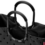 Nahaufnahme einer schwarzen Tasche mit glänzenden Punkten und robusten, ovalen Griffen. Die Perspektive zeigt die obere Hälfte der Tasche mit Fokus auf die Griffe und den Reißverschluss.