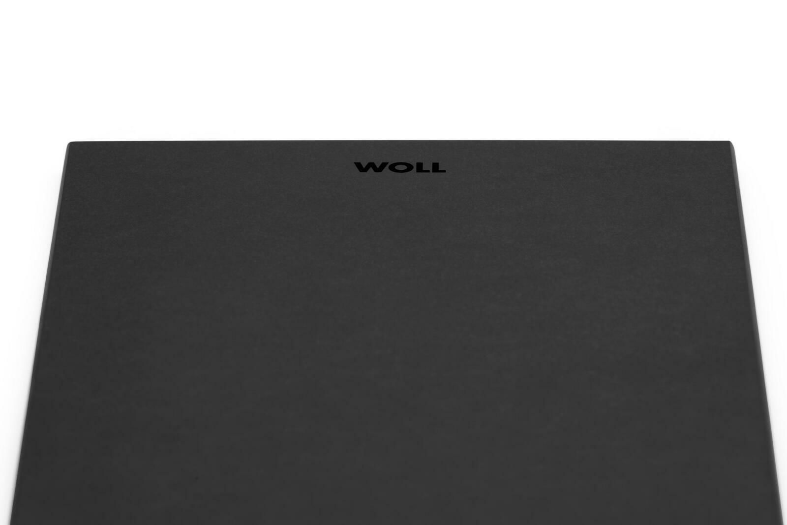 Nahaufnahme eines schwarzen rechteckigen Frühstücksbretts mit dem Logo 'WOLL' in der Mitte.