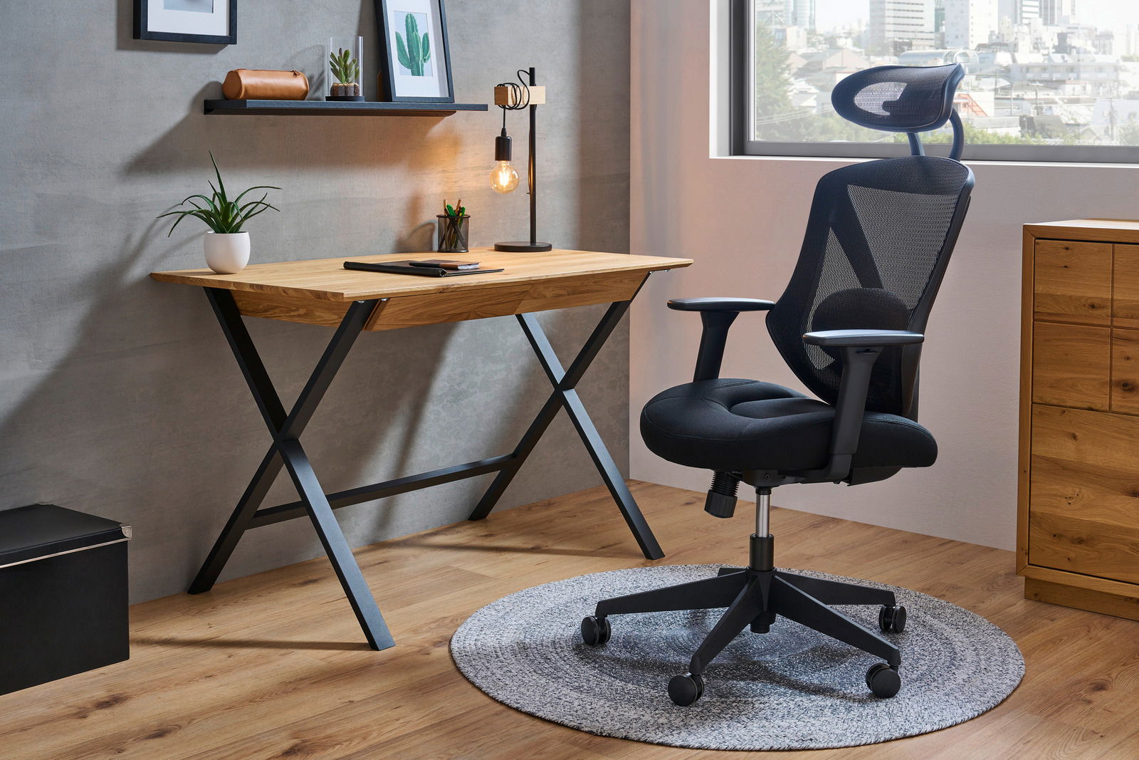 Moderner Schreibtisch aus Holz mit schwarzem Metallgestell, seitliche Perspektive, dekoriert mit Pflanze und Lampe.