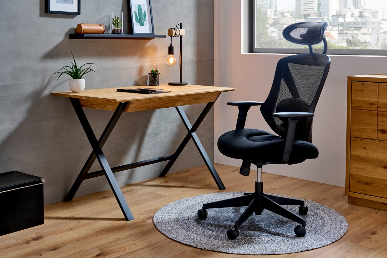 Moderner Schreibtisch aus Holz mit schwarzem Metallgestell, seitliche Perspektive, dekoriert mit Pflanze und Lampe.