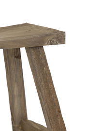 Nahaufnahme eines rustikalen Holz-Hockers aus seitlicher Perspektive, der die natürliche Maserung und Struktur des Holzes zeigt.