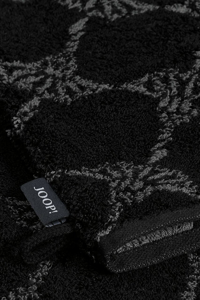 JOOP! Waschhandschuh 16x22cm CORNFLOWER CLASSIC Nahaufnahme eines schwarzen Waschhandschuhs mit grauem Muster und einem Joop!-Label.